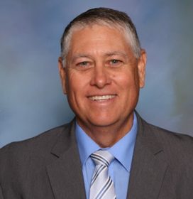Profile picture of Kindel Mason wearing a dark grey suit jacket, blue dress shirt, and grey tie.